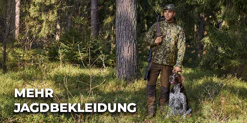 Jäger in Tarnkleidung steht mit einem Gewehr neben seinem Hund in einem sonnendurchfluteten Nadelwald; links unten steht der Schriftzug ‚Mehr Jagdbekleidung‘.