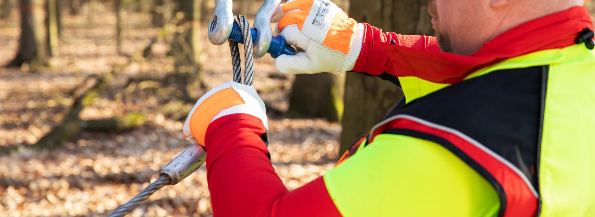 Waldarbeiter befestigt ein Stahlseil an einem Schäkel